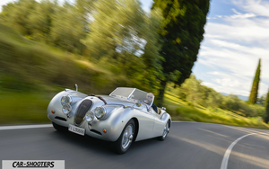 Jaguar XK 120 Retina – front three-quarter, silver on a country road