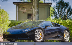Lamborghini Huracan Retina – front three-quarter, black against a rustic building backdrop