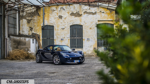 Lotus Elise WALLAPER1 Fullhd – front three-quarter, dark blue in front of an old building