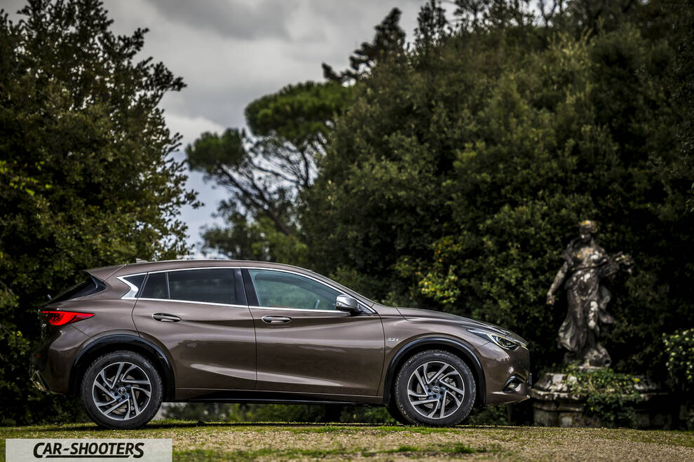 Infiniti Q30 – side profile, bronze metallic against a lush green park backdrop