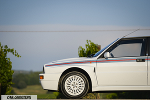 Lancia Delta HF Integrale Martini 5 – side profile, white against a countryside backdrop
