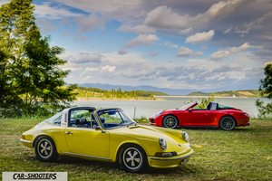 Porsche 911 Targa Storica – front three-quarter, yellow against a scenic lake backdrop