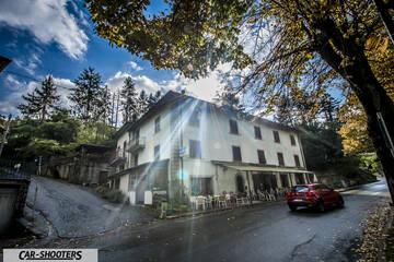 Alfa Romeo Mito Veloce Imola Mugello – rear three-quarter, red parked by a building on a wet street