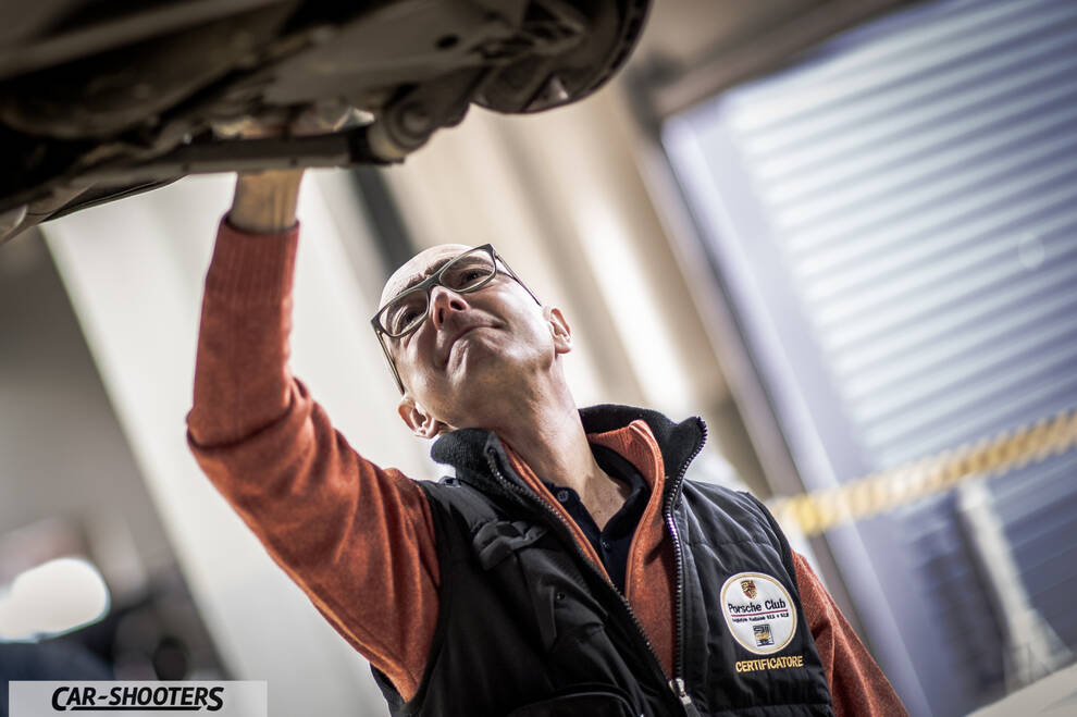 Porsche – detail, mechanic inspecting undercarriage in a garage