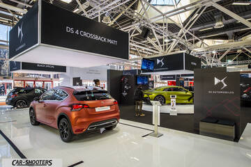 rear three-quarter, matte orange in an auto show exhibit
