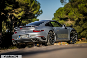 Porsche 911 Turbo S – rear three-quarter, silver metallic against a wooded backdrop