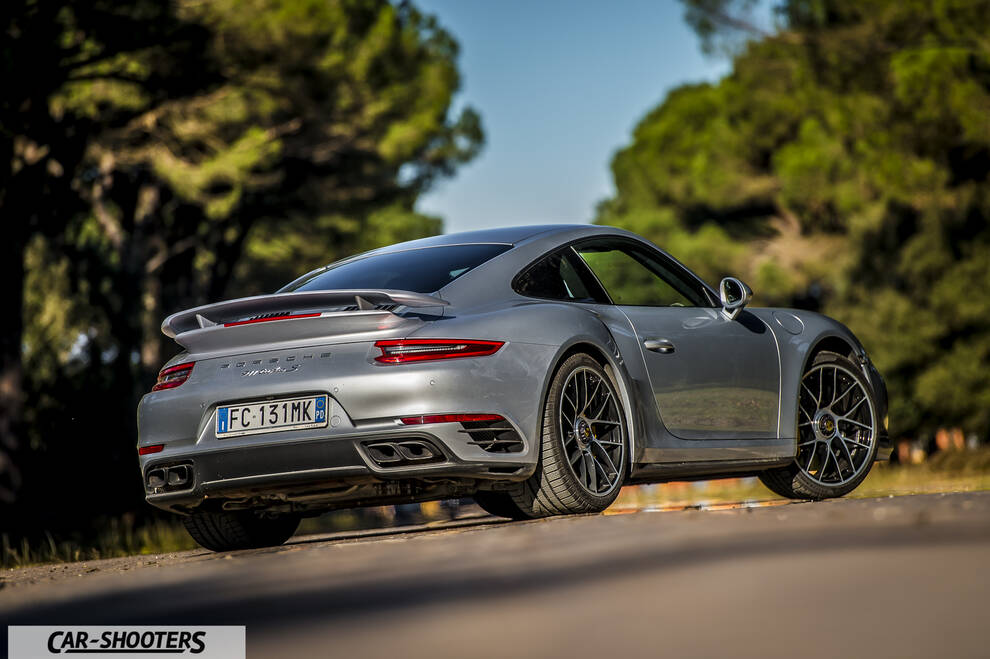 Porsche 911 Turbo S – rear three-quarter, silver metallic against a wooded backdrop