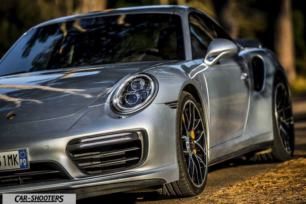 Porsche 911 Turbo S – front three-quarter, silver against a blurred park backdrop