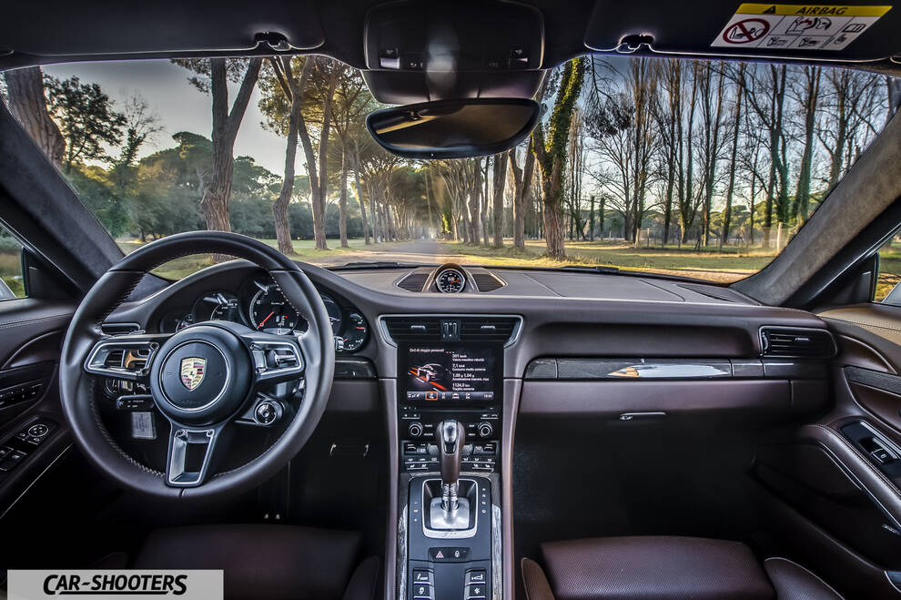 Porsche 911 Turbo S – dashboard, view through windshield of tree-lined road