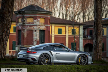 Porsche 911 Turbo S – rear three-quarter, silver metallic against a historic building backdrop
