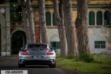 Porsche 911 Turbo S – rear view, silver against an old building backdrop