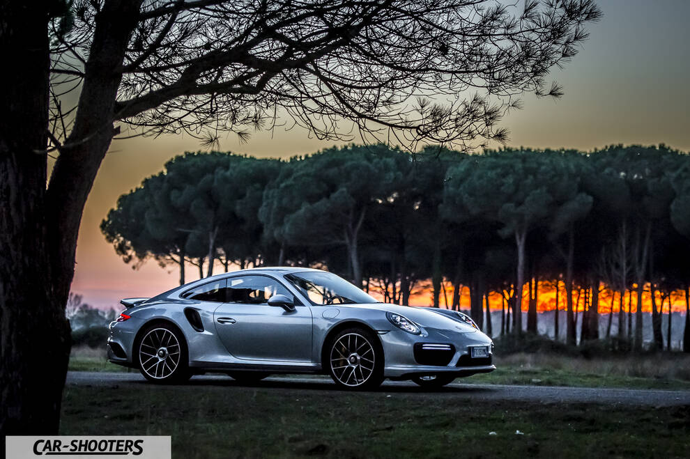 Porsche 911 Turbo S – side profile, silver against a sunset tree line