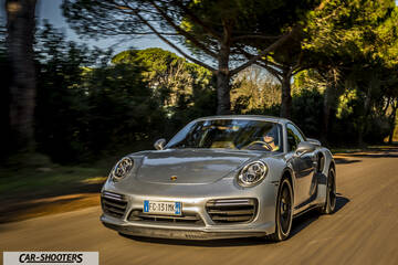 Porsche 911 Turbo S – front three-quarter, silver driving on a road with trees