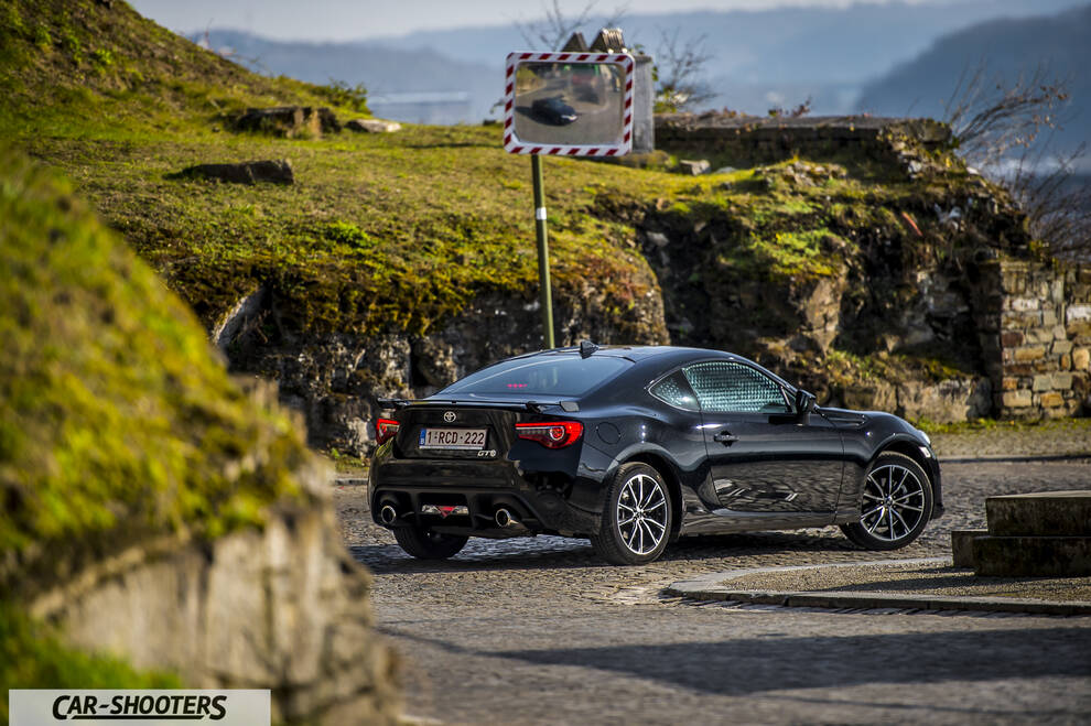Toyota GT86 Namur – rear three-quarter, black against a grassy hill