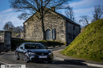 Toyota GT86 Namur – front three-quarter, black on a cobbled street before a stone building
