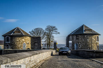 Toyota GT86 Namur – front three-quarter, black on a cobblestone path between stone towers