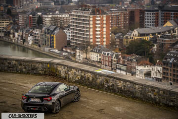 Toyota GT86 Namur – rear three-quarter, black against an urban hillside backdrop
