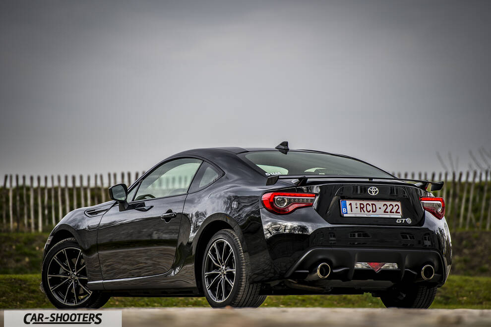 Toyota GT86 Namur – rear three-quarter, black against a wooden fence