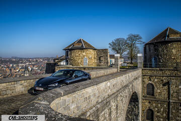 Toyota GT86 Namur – front three-quarter, black on a historic stone bridge