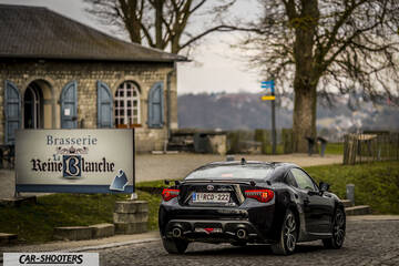 Toyota GT86 Namur – rear three-quarter, black parked near a brasserie building
