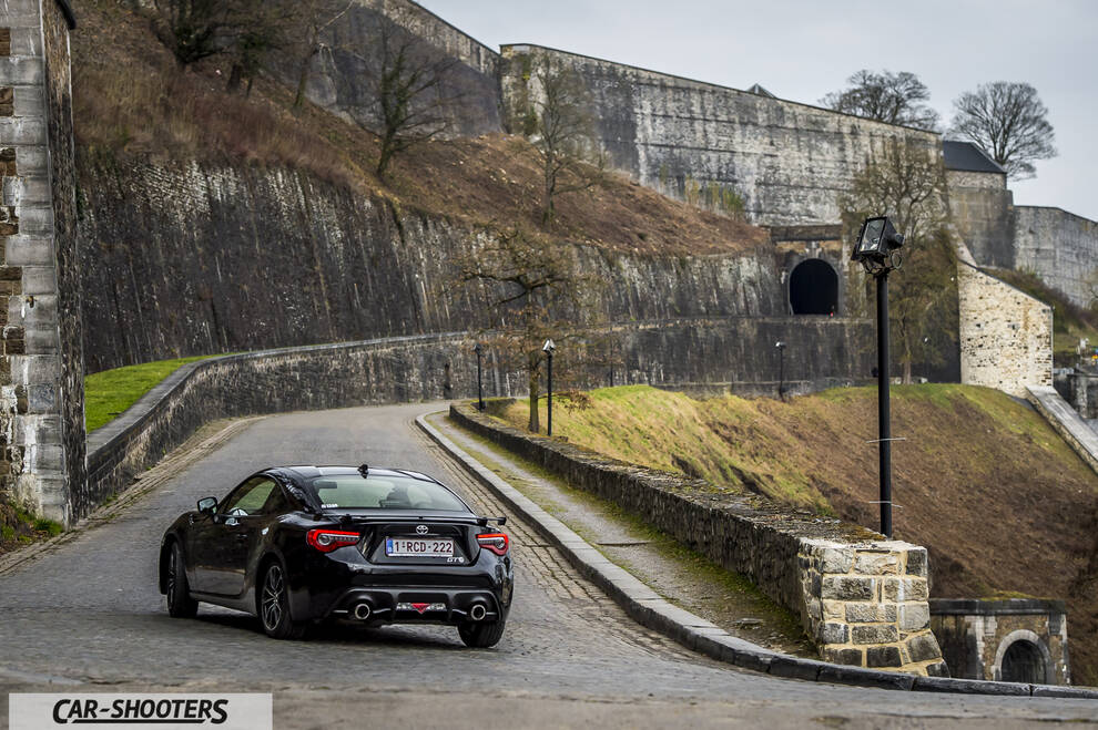 Toyota GT86 Namur – rear three-quarter, black against an old stone fortress backdrop