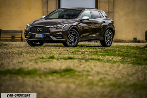 Infiniti Q30 – front three-quarter, brown metallic parked on a gravel courtyard
