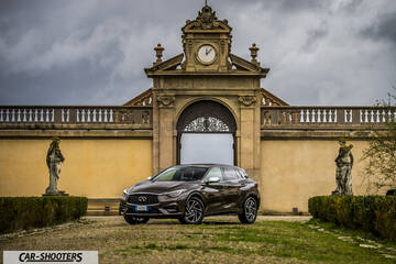 Infiniti Q30 – front three-quarter, brown metallic against a historic stone building