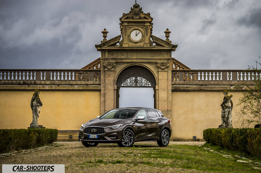 Infiniti Q30 – front three-quarter, brown metallic against a historic stone building
