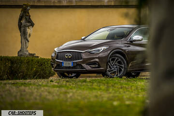 Infiniti Q30 – front three-quarter, brown metallic against a yellow wall