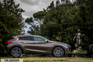 Infiniti Q30 – side profile, bronze metallic against a lush green park backdrop