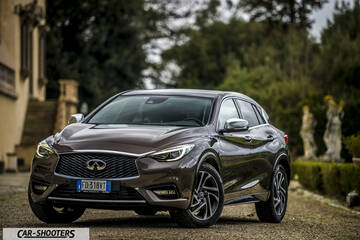 Infiniti Q30 – front three-quarter, brown metallic parked near an old building