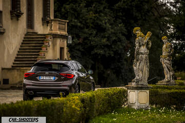Infiniti Q30 – rear three-quarter, brown metallic in front of an old villa