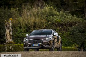Infiniti Q30 – front three-quarter, brown metallic on a park road with a statue