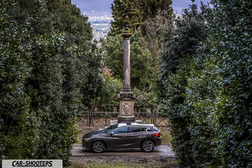 Infiniti Q30 – side profile, brown metallic on a pathway framed by trees