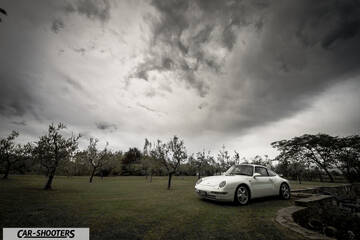 Porsche 993 Carrera 4 – front three-quarter, white against a stormy sky