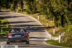 Fiat 124 Spider – rear view, dark grey on a winding country road