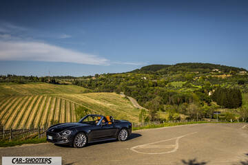 Fiat 124 Spider – side profile, dark blue against a mountain backdrop