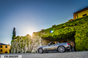 Fiat 124 Spider – rear three-quarter, grey metallic against a stone and vine wall