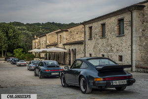 Porsche 911 e 912 – rear three-quarter, dark green metallic parked in front of a stone building