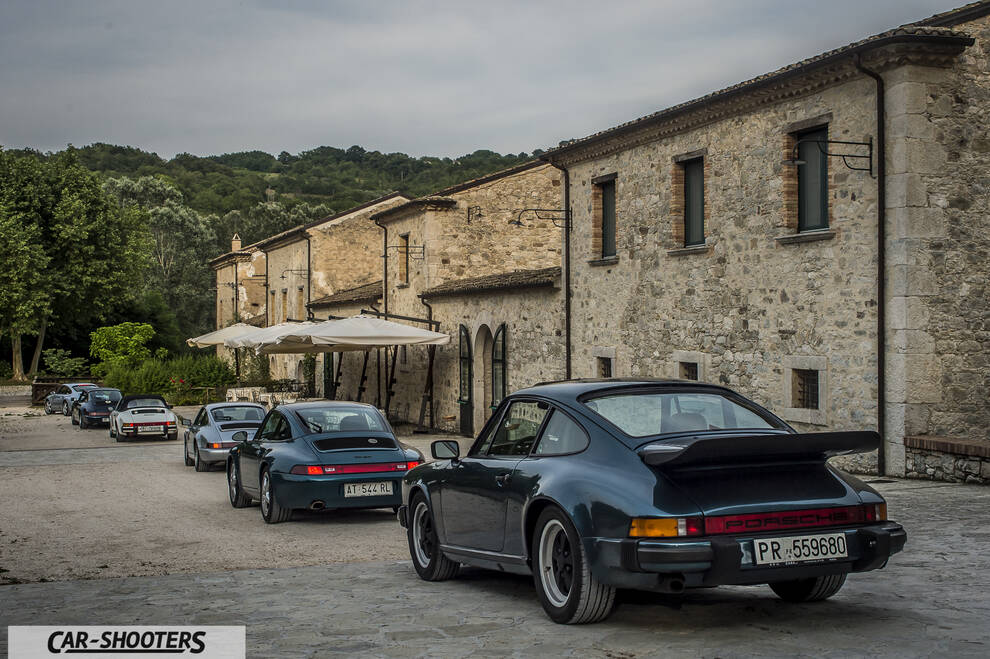 Porsche 911 e 912 – rear three-quarter, dark green metallic parked in front of a stone building
