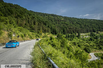 rear three-quarter, bright blue on a mountain road