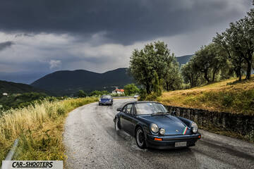 front three-quarter, blue metallic on a winding country road