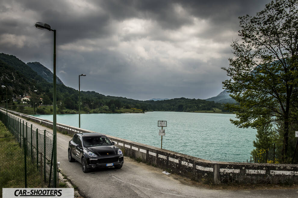 Porsche 911 e 912 – front three-quarter, black on a road by a lake