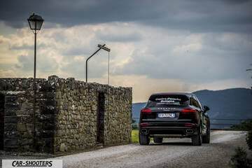 Porsche Cayenne Platinum Edition – rear view, black on a dirt road against a mountain backdrop