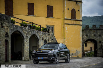 Porsche Cayenne Platinum Edition – front three-quarter, black parked against an old building
