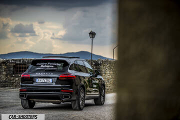 Porsche Cayenne Platinum Edition – rear three-quarter, black against a stone wall and hills
