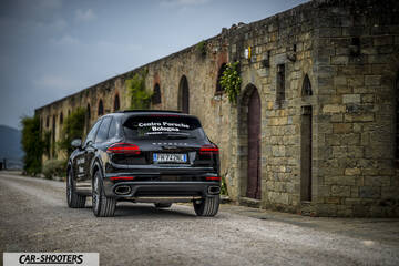 Porsche Cayenne Platinum Edition – rear three-quarter, black parked against an old stone building