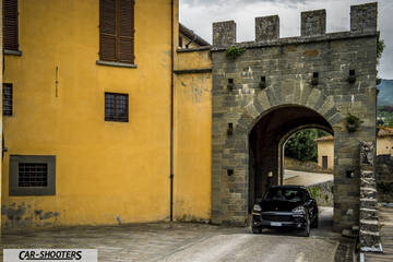 Porsche Cayenne Platinum Edition – front three-quarter, black driving through a stone archway