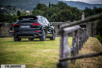Porsche Cayenne Platinum Edition – rear three-quarter, black against a stone wall and fence