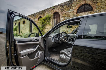 Porsche Cayenne Platinum Edition – side profile, black parked against a stone building
